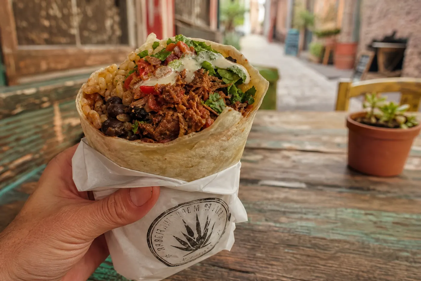 Vegan burrito with jackfruit, beans, rice, greens, and crema